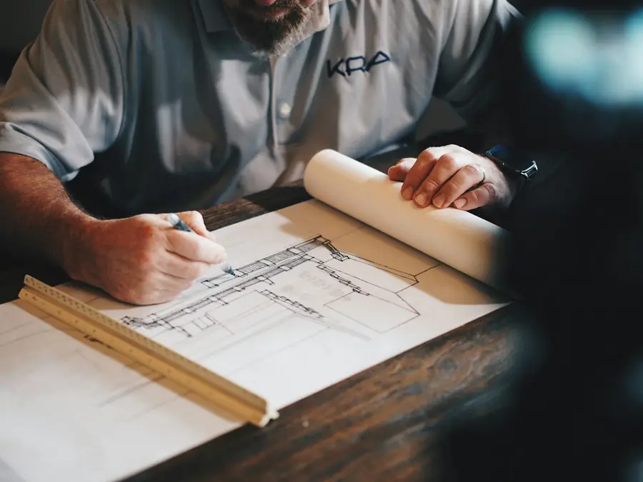 Profesional trazando planos arquitectónicos sobre una mesa de trabajo