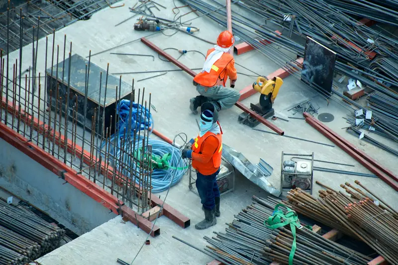 Obreros con casco trabajando entre el armado de hierro de una obra nueva
