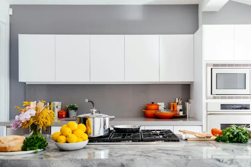 Cocina moderna recién remodelada con mesón de mármol y muebles blancos